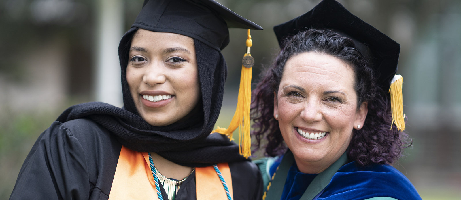 A professor and student wearing regalia at commencement.